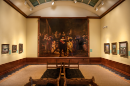 Formal art gallery with framed paintings hanging on the walls under a frosted glass ceiling